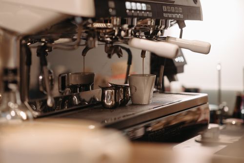 Two-group espresso machine pulling shots into cups (generic illustration)