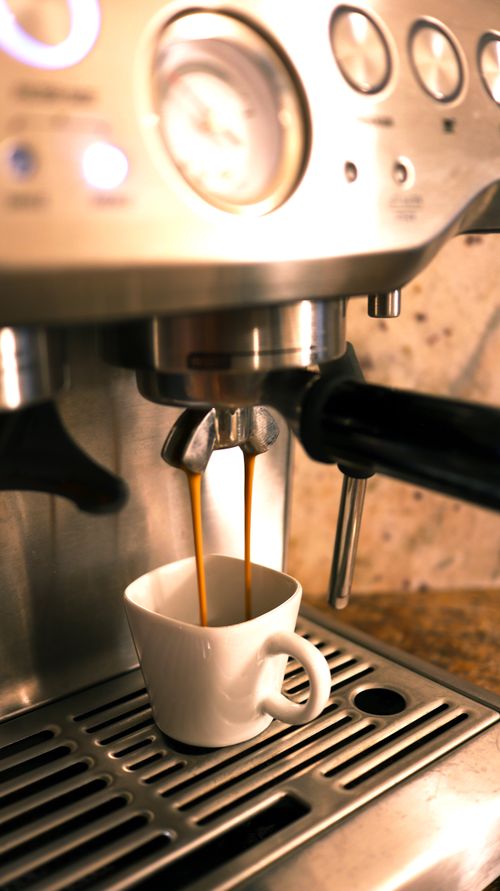 Espresso machine pulling a shot into a cup on a wooden counter (generic illustration)