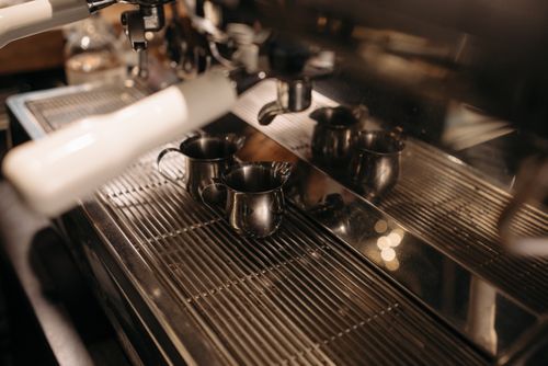 Espresso machine with steam wand and metal milk pitchers (generic illustration)